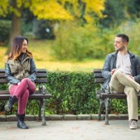 hombre y mujer sonrientes sentados en el banco del parque