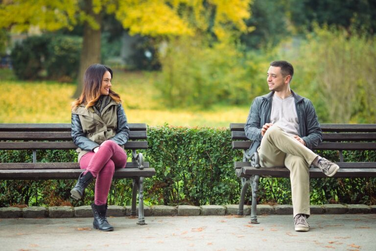 homem e mulher sorridentes sentados num banco de jardim