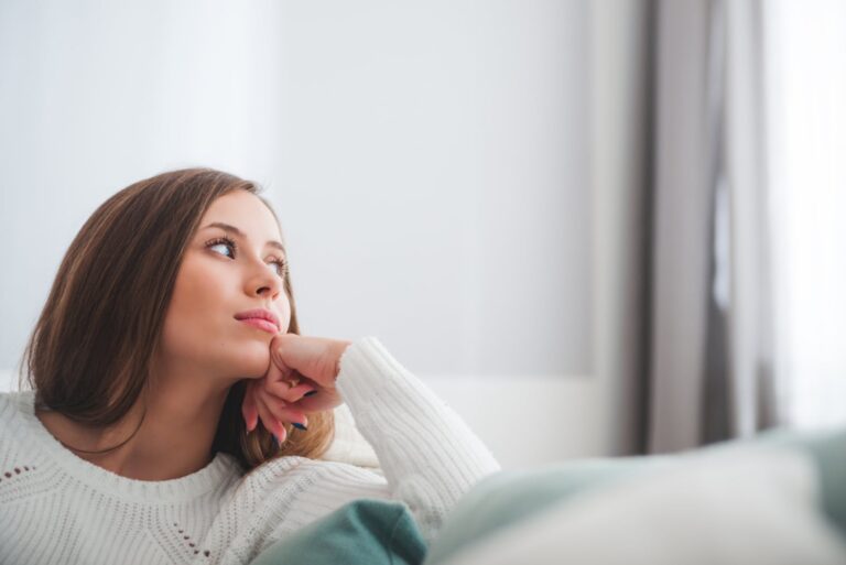 mujer pensativa en casa mirando a la ventana