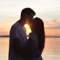 casal a beijar-se ao pôr do sol