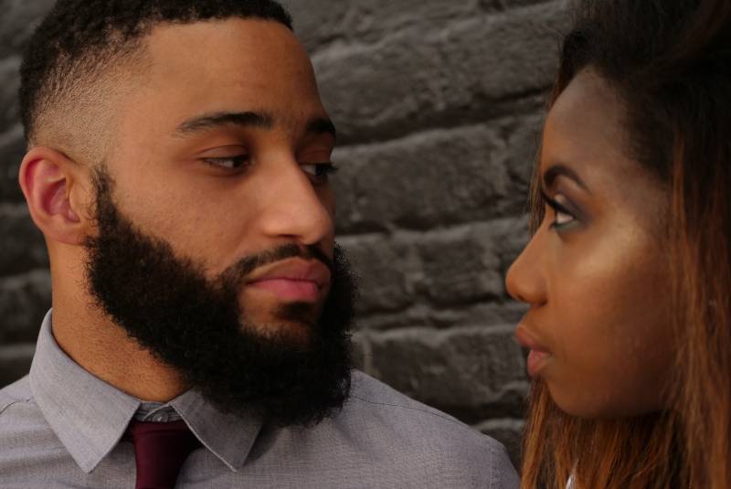 Man stares at woman near gray wall