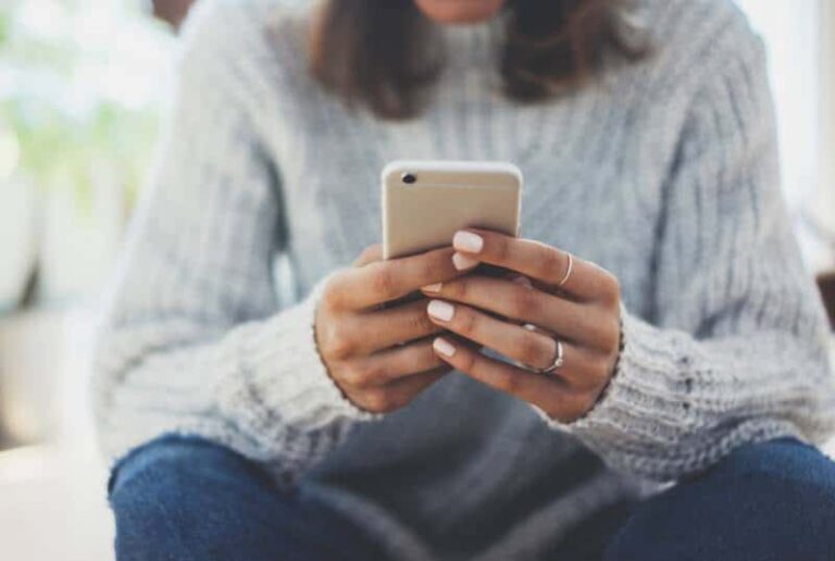 donna seduta a casa che usa lo smartphone
