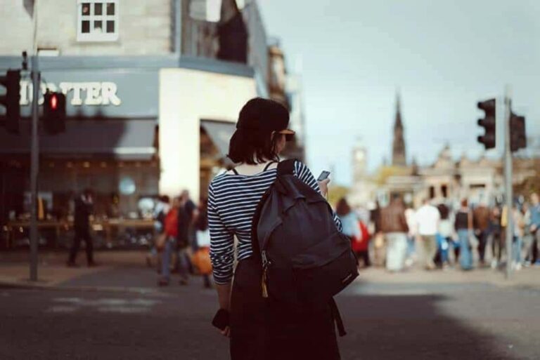 una mujer de pelo castaño con un teléfono en la mano se para en la calle