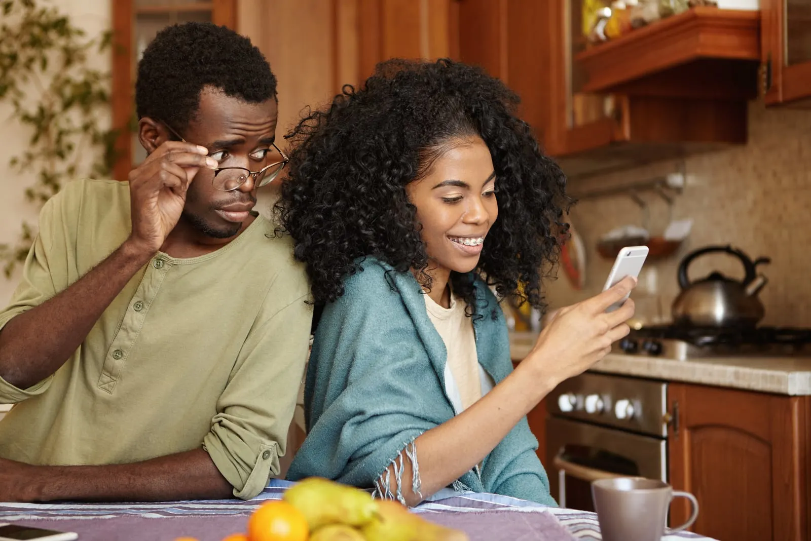 a jealous black man peeks into the contents of his wife's smartphone