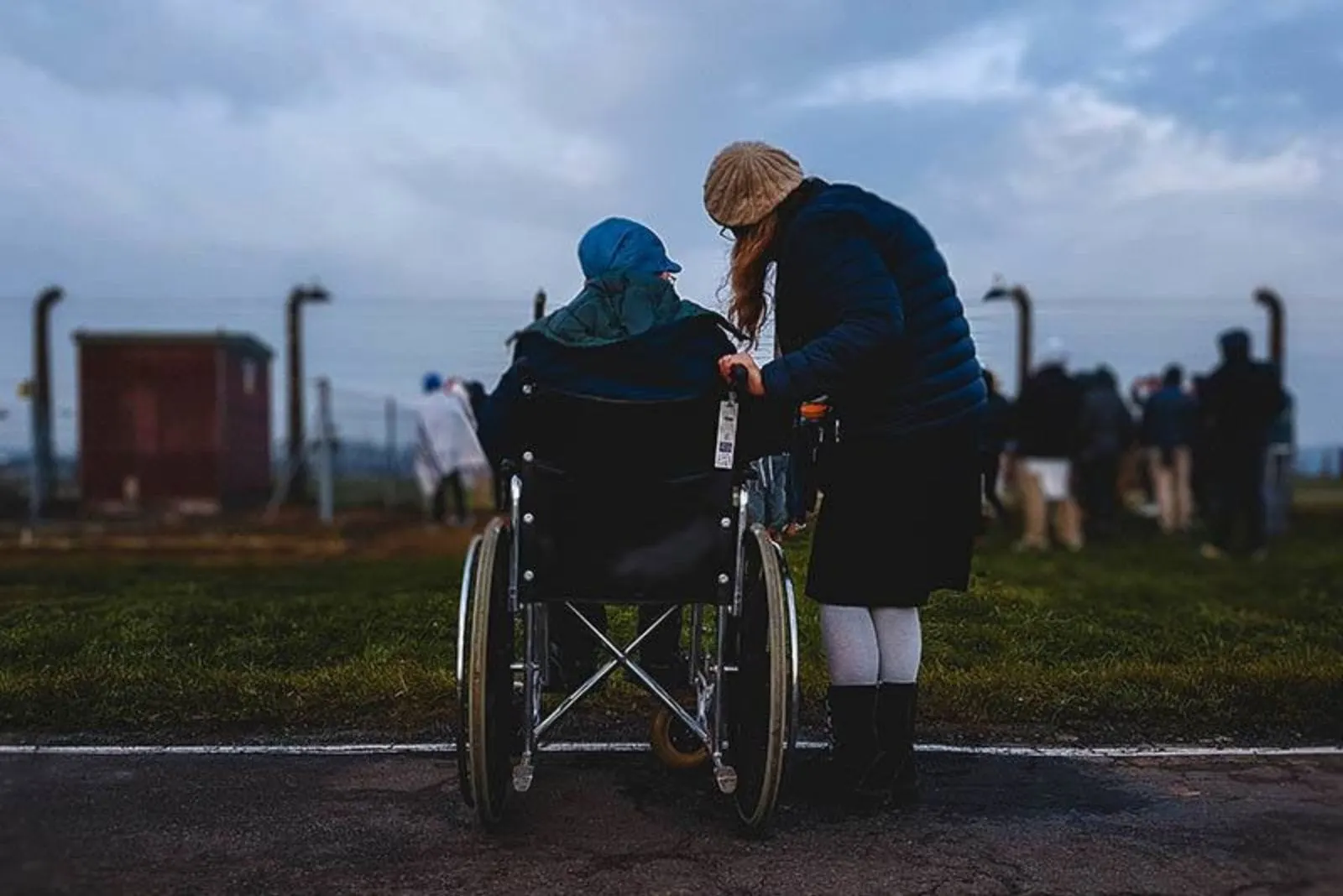 a woman standing with a man in a wheelchair