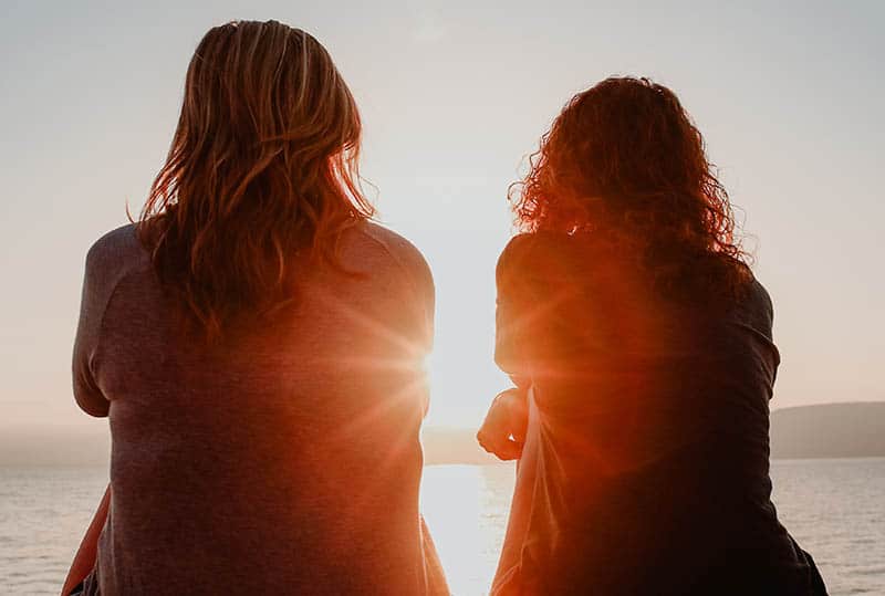 close up photo of females sitting in front of sea