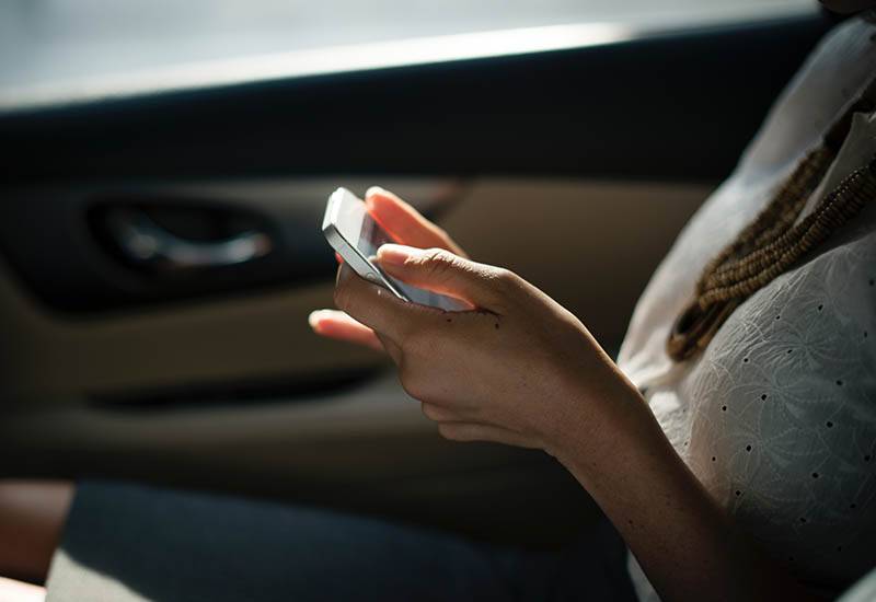 close up photo of woman typing a on her phone in car