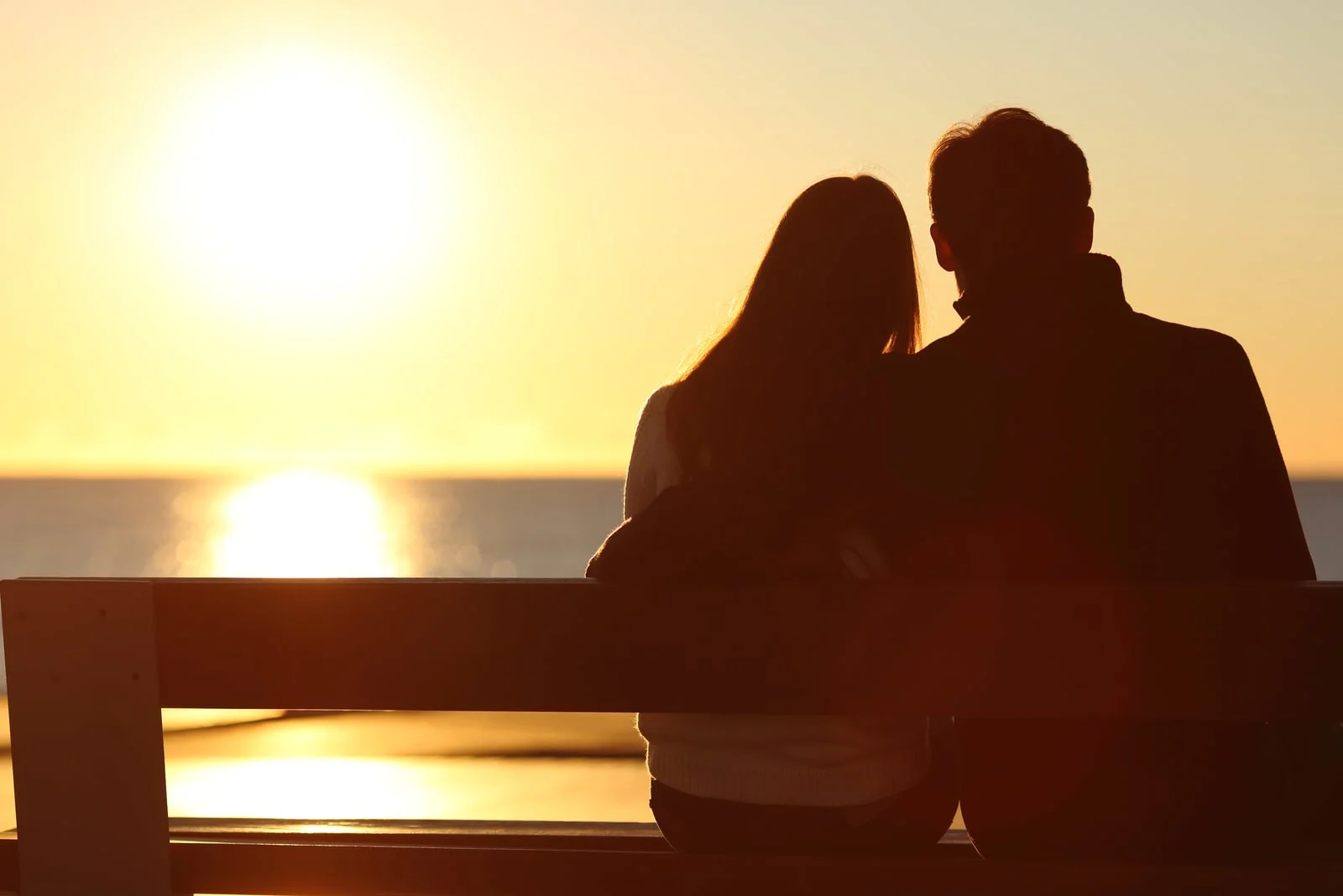 couple hugging and watching sun on the beach