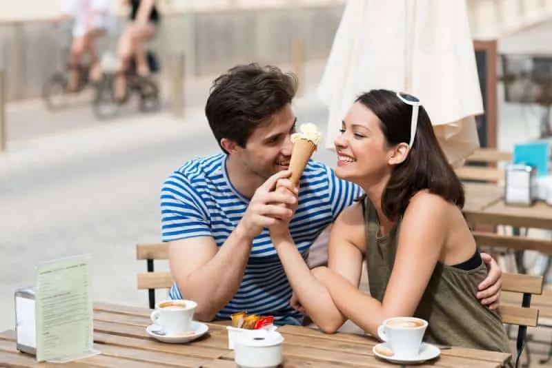couple share an ice cream at a street cafe