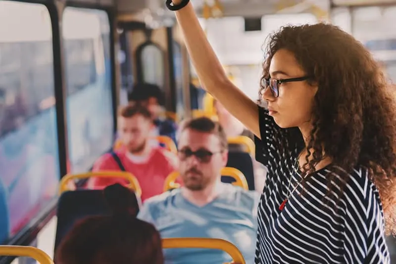 curly hair woman wearing eyeglasses while standing in public transport