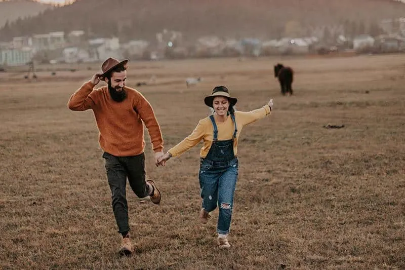 man and woman holding hands and running