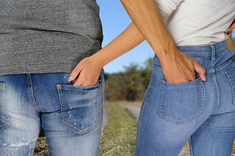 hombre y mujer metiendo las manos en el bolsillo trasero