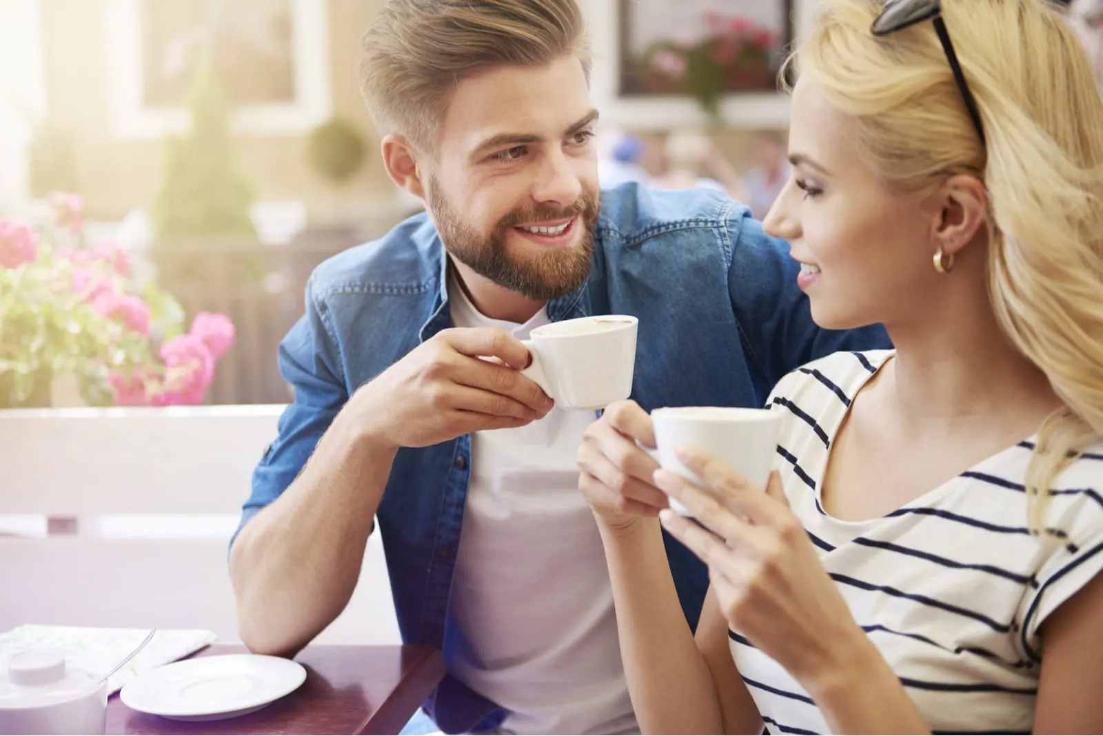 man with beard drinking coffee and talking with woman