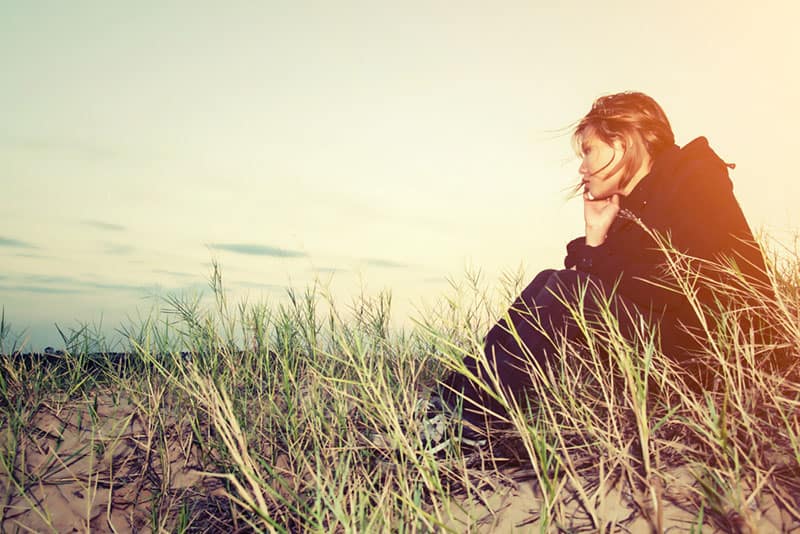 sad young woman sitting on the grass