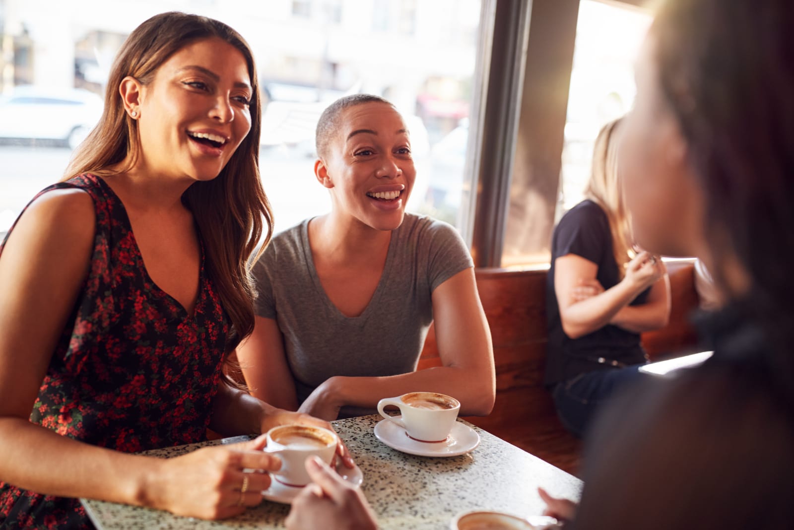tre amici sorridenti che bevono caffè in un bar e parlano