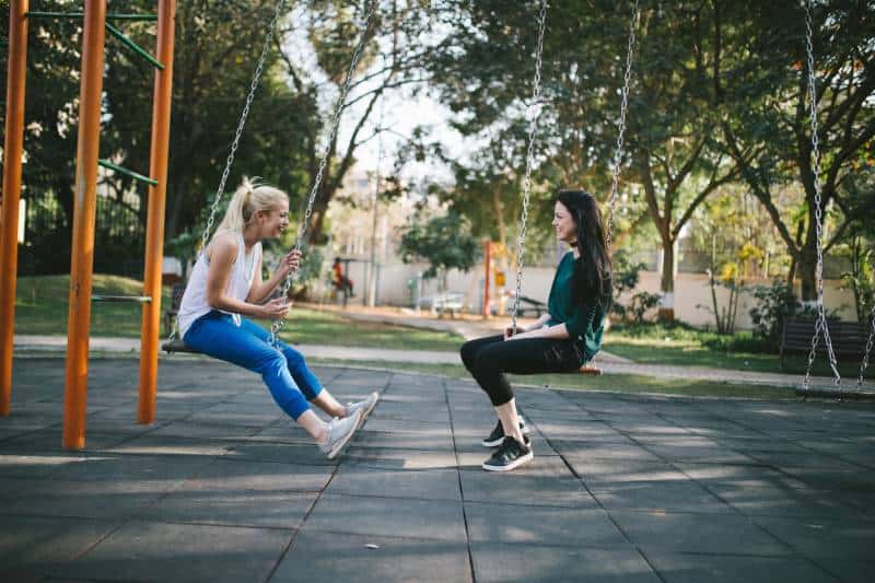 two girls sitting on swing