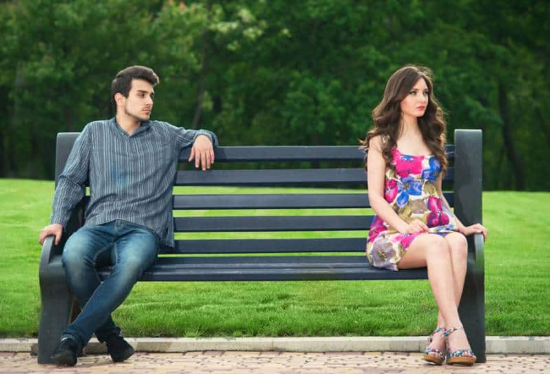coppia infelice seduta sulla panchina del parco