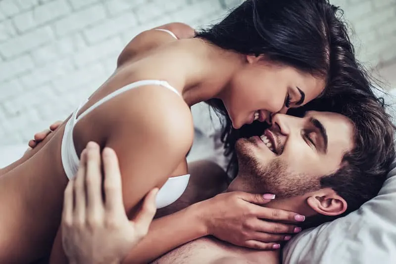 woman wearing bra kissing man in bed