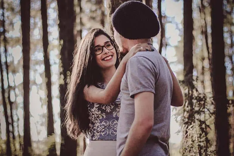 young woman wearing glasses hugging man