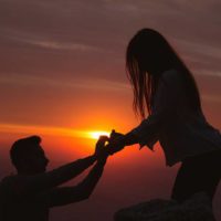 silhouette side view of man and woman touches their hands