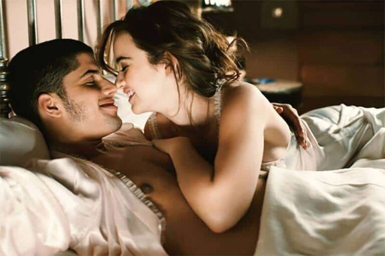 lovely couple lying on bed going to kiss