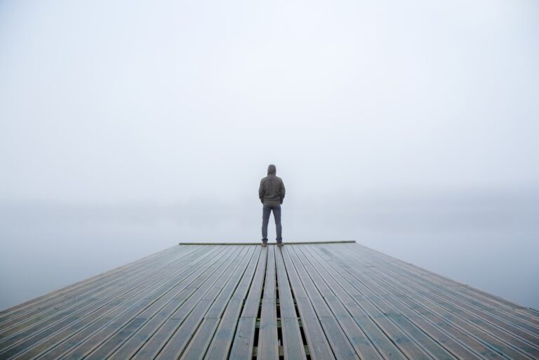 young guy standing and staring at the lake