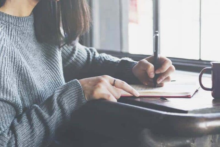 close up photo of woman writing a letter at home