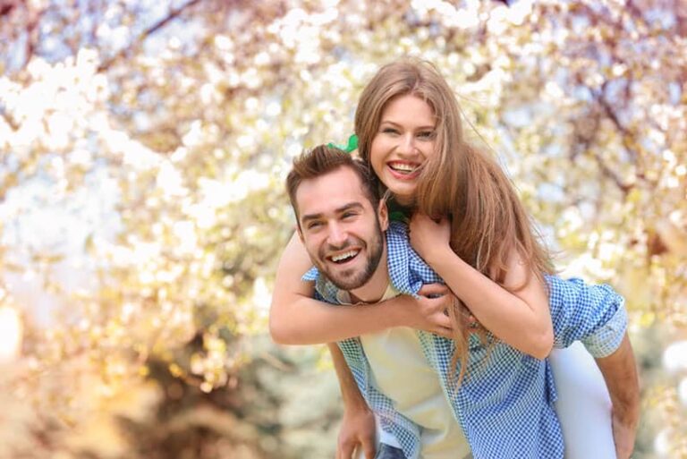 hombre sonriente con mujer a cuestas
