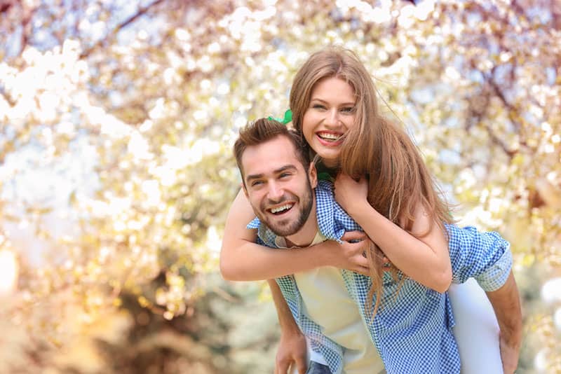 smiling man carryng woman on his back