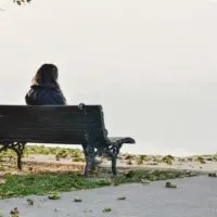 sad woman in nature sitting on the bench