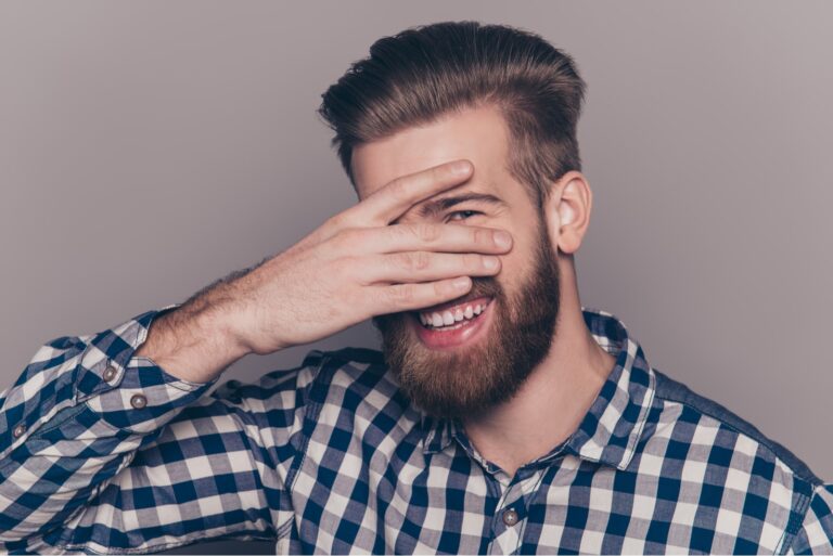 Funny cute young man with beard hiding his face