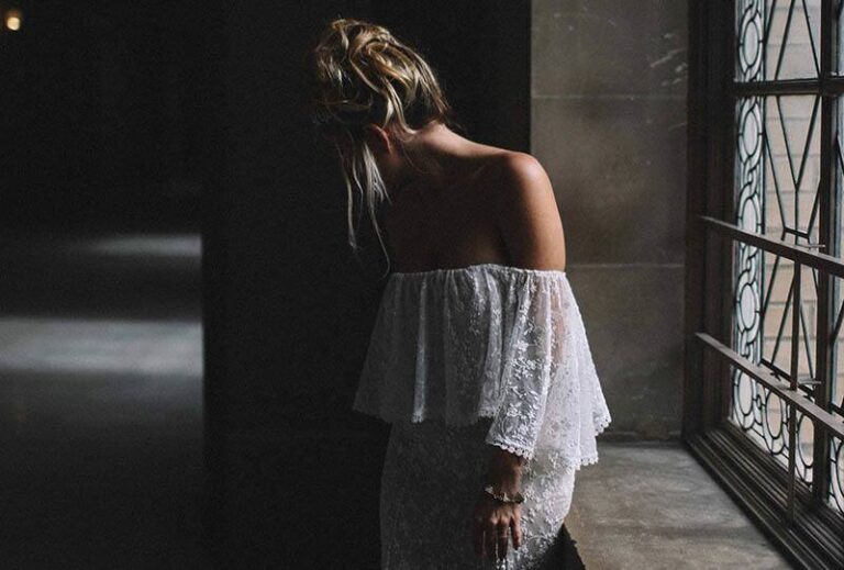 uma mulher de vestido branco com um olhar abatido