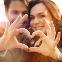 adorable pareja haciendo forma de corazón con las manos