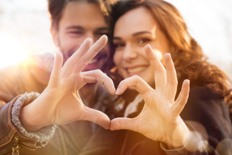 casal encantador a fazer a forma de um coração com as mãos