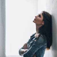 thoughtful woman leaning on wall