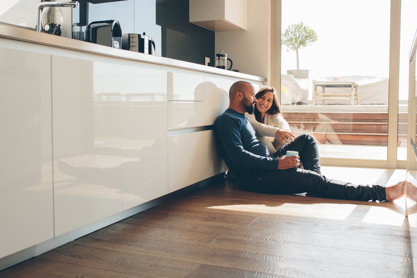 a happy loving couple sitting on the kitchen floor