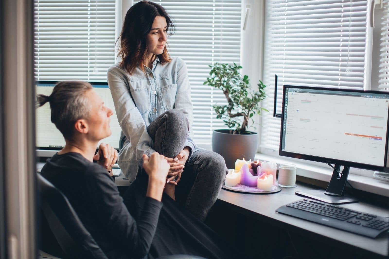 a man and a woman in the office are watching something on a laptop