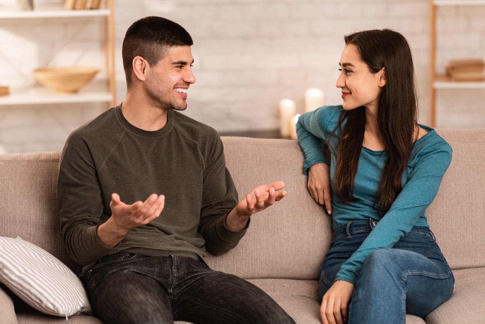 a smiling couple sitting on the couch and talking