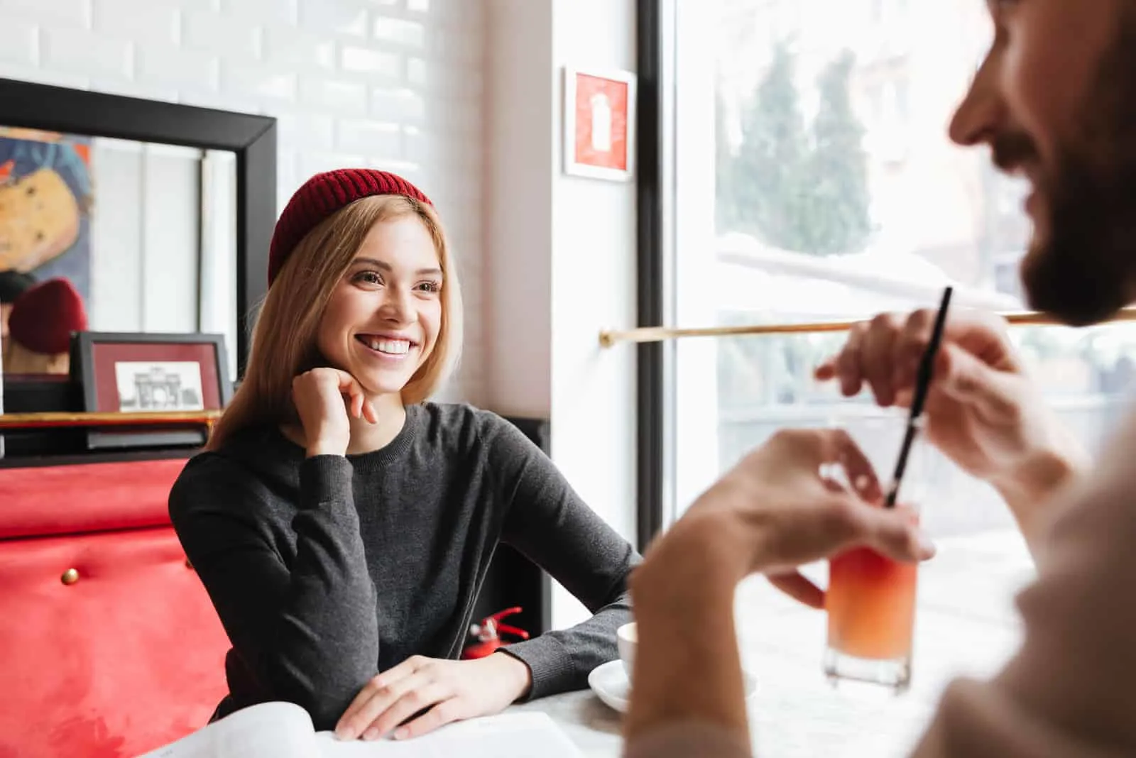 a smiling woman sits in a cafe and talks to a man