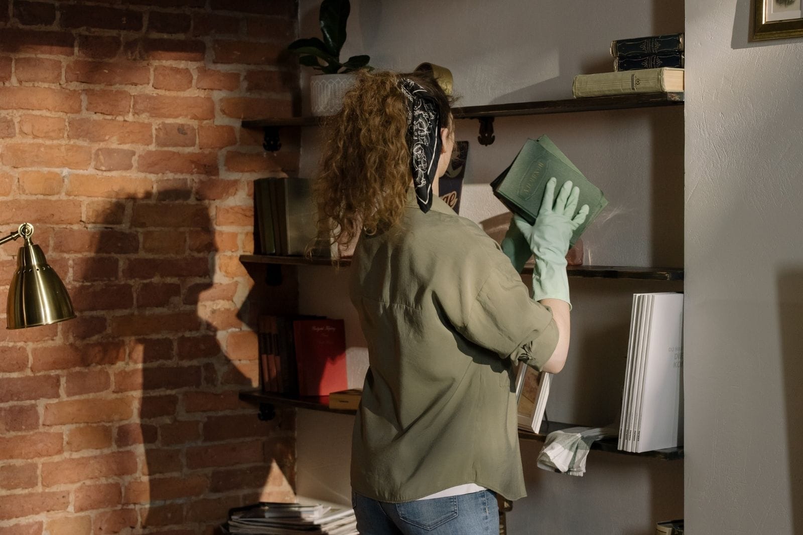 a woman in rubber gloves cleans bookshelves