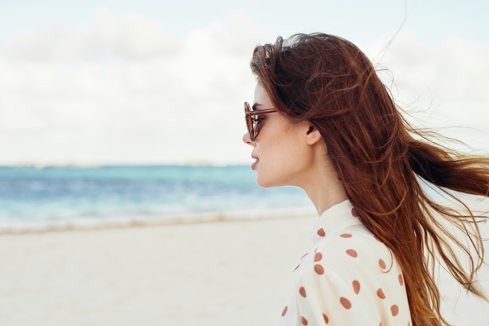 a woman with long brown hair and glasses looks away