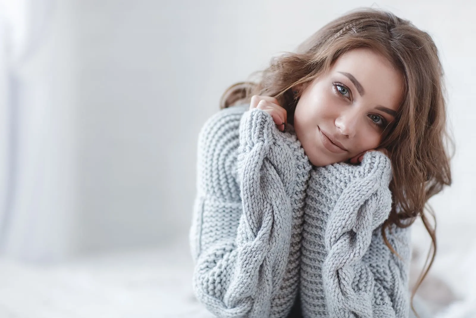 a woman with long brown hair with a gray sweater