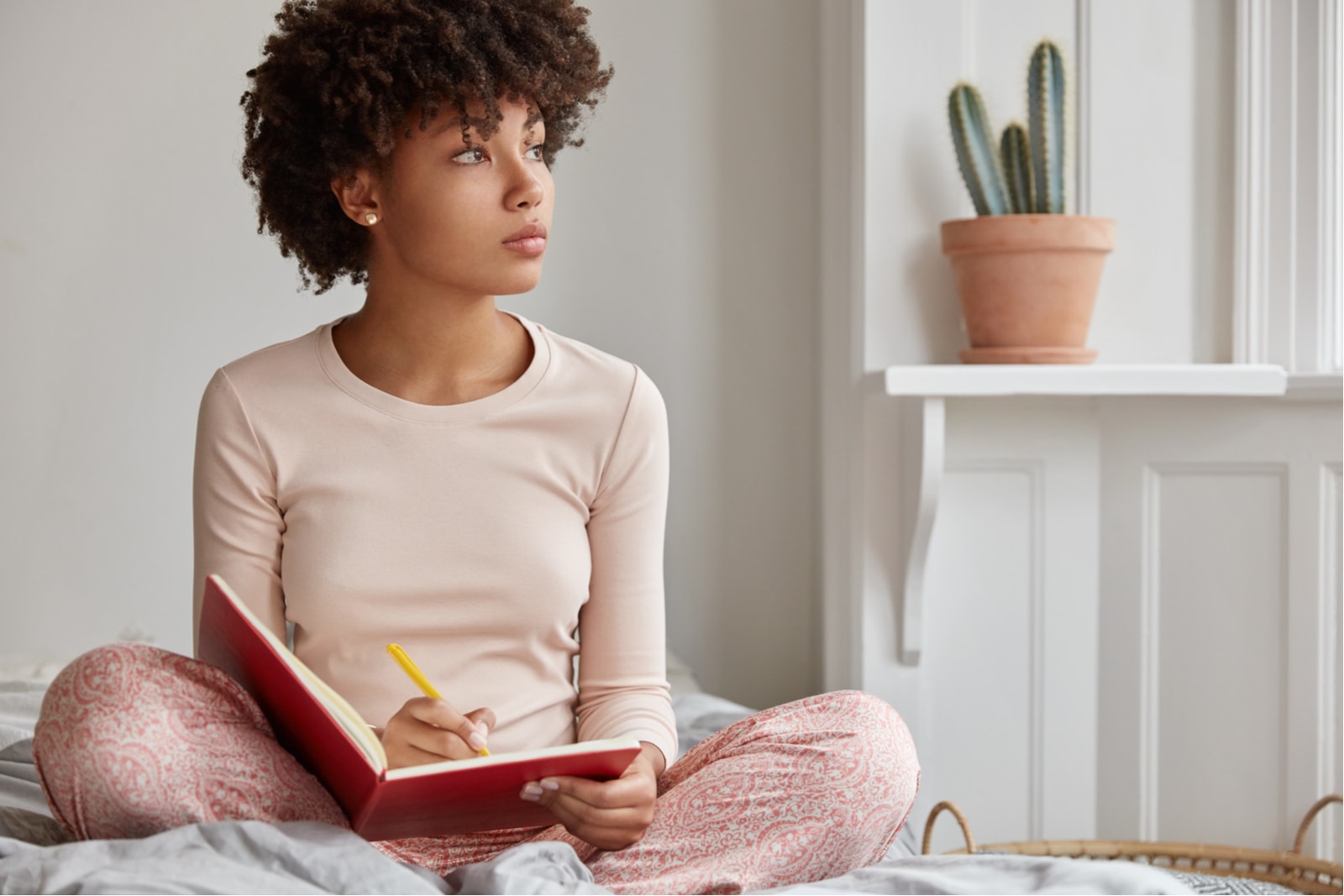 una atractiva mujer negra está sentada en la cama y escribiendo algo