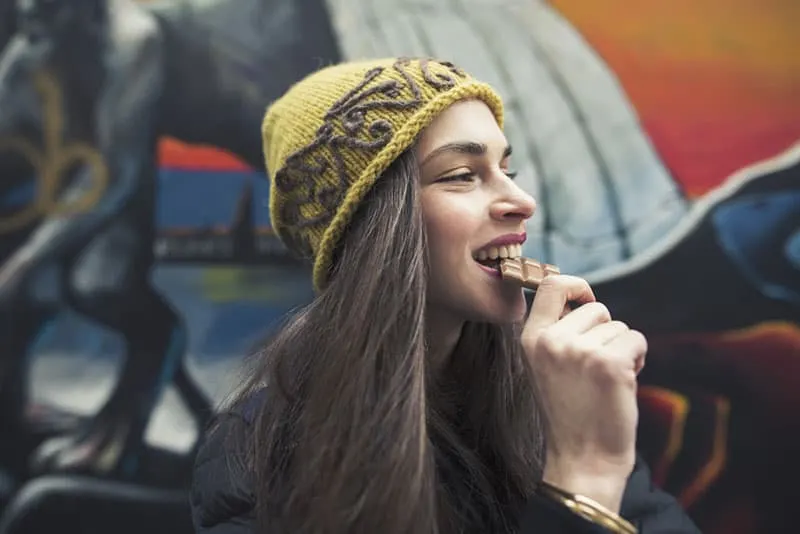 beautiful young woman biting a chocolate bar