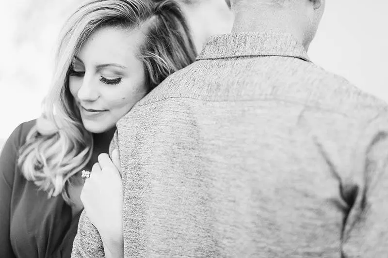 black and white photo of happy woman hugs man's arm