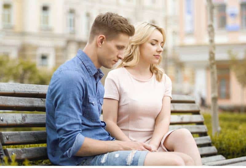 una pareja se siente incómoda sentada en un banco en silencio