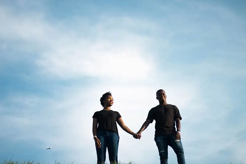 couple holding their hands with sky in background