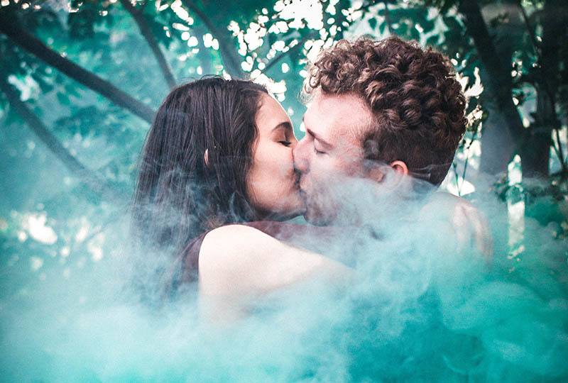 couple kissing outside surrounded by a smoke