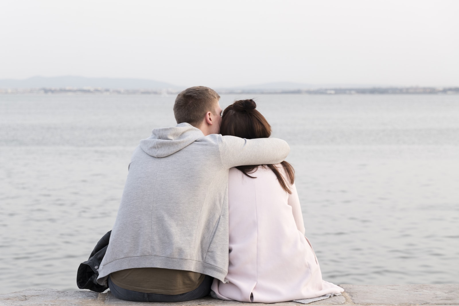 pareja sentada junto al río abrazándose