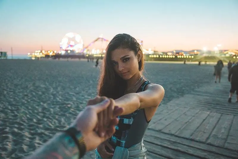 man holds woman hand on the beach